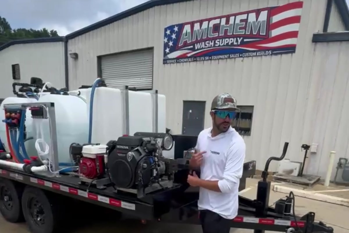 AmChem team member explaining a finished pressure washing trailer outside the Woodstock shop